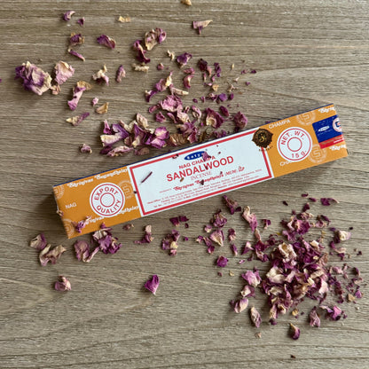 Box of Sandalwood incense sticks with scattered sandalwood chips on a wooden surface