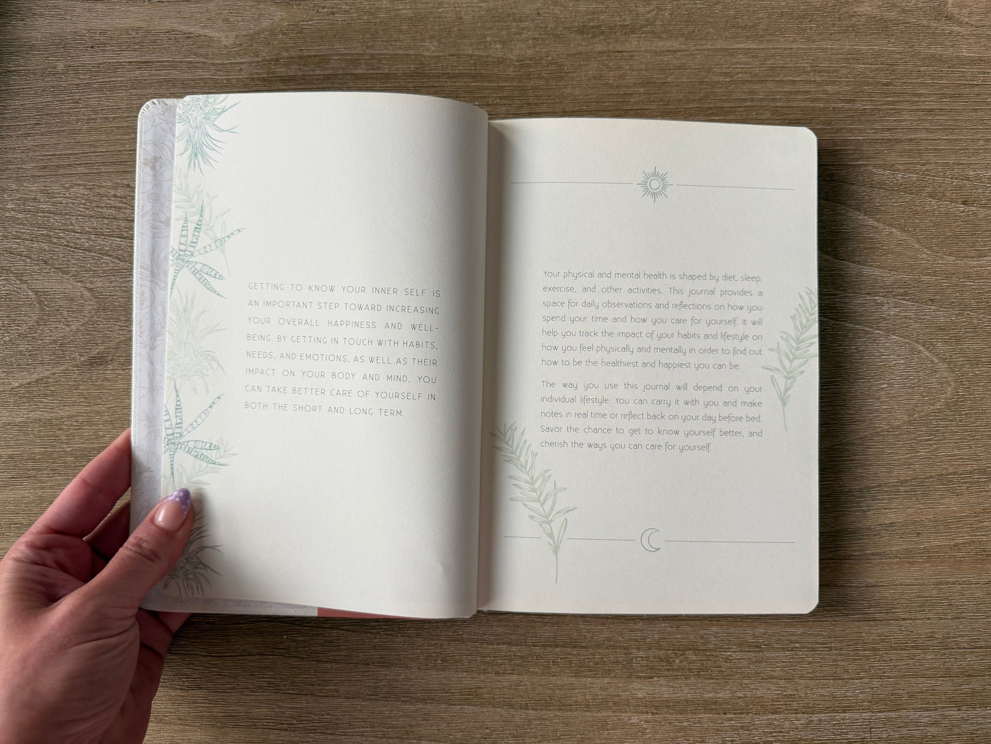 Open book on a wooden surface with a hand holding it open