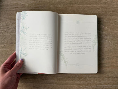 Open book on a wooden surface with a hand holding it open