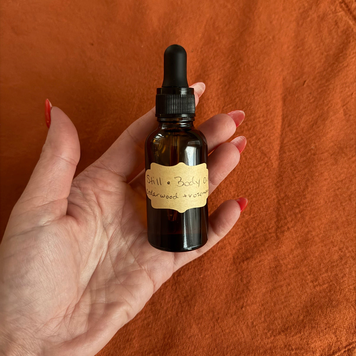 small glass oil bottle holding body oil with cedarwood and rosemary
