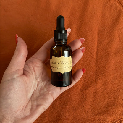 small glass oil bottle holding body oil with cedarwood and rosemary