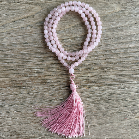 Pink beaded necklace with tassel on a wooden surface