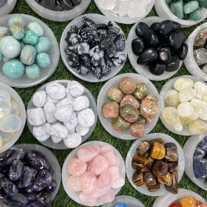 Assorted types of gemstones in small bowls on a grassy background